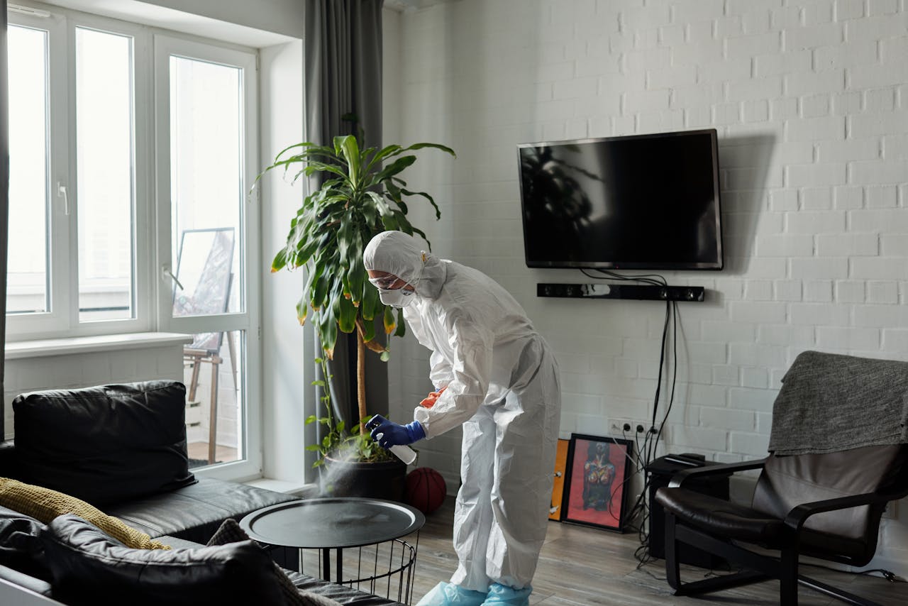 services-02 Worker in PPE disinfecting a living room, ensuring safety from viruses.